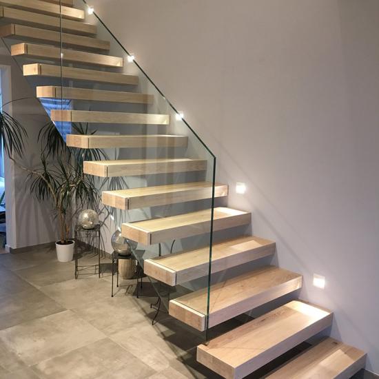 Beleuchtete Kragarmtreppe mit Holzstufen und Glasgeländer von Treppenbau SEIFERT